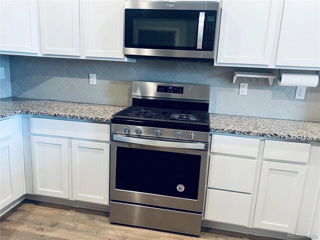 14673 E Belleview Dr, Aurora, CO 80015 - kitchen with appliances with stainless steel finishes, white cabinetry, light stone counters, and light wood-style floors