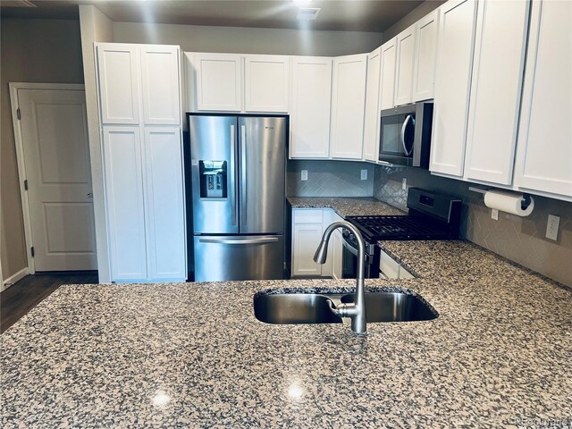 14673 E Belleview Dr, Aurora, CO 80015 - kitchen featuring appliances with stainless steel finishes, a sink, dark stone counters, white cabinetry, and backsplash