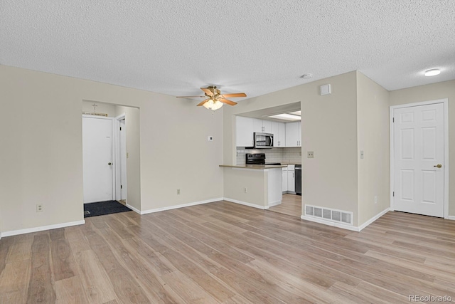unfurnished living room featuring a textured ceiling, light wood-style flooring, a ceiling fan, and baseboards