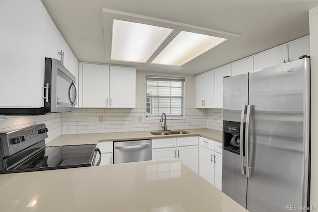 kitchen featuring stainless steel appliances, a sink, tasteful backsplash, and white cabinets