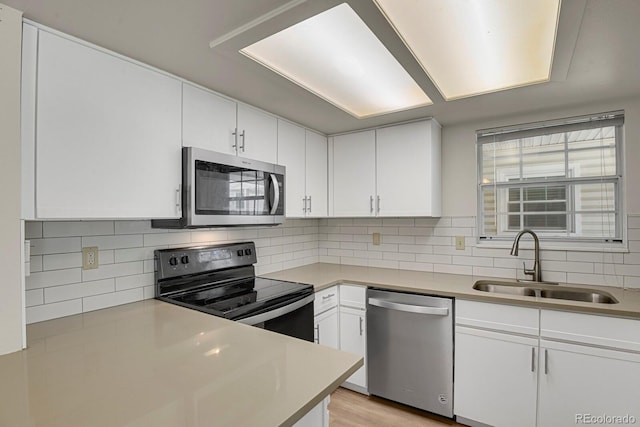 kitchen featuring appliances with stainless steel finishes, a sink, white cabinetry, and light countertops