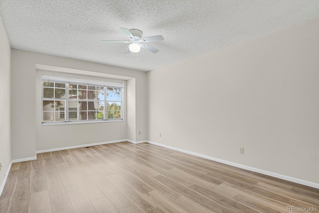 spare room with ceiling fan, light wood-type flooring, a textured ceiling, and baseboards