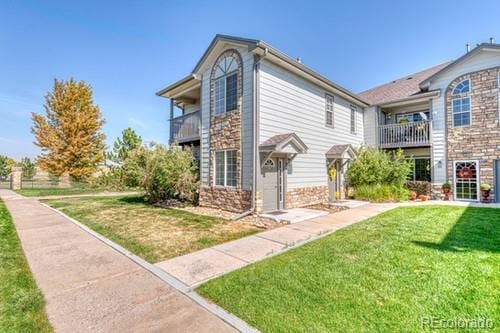 exterior space with a balcony and a front yard