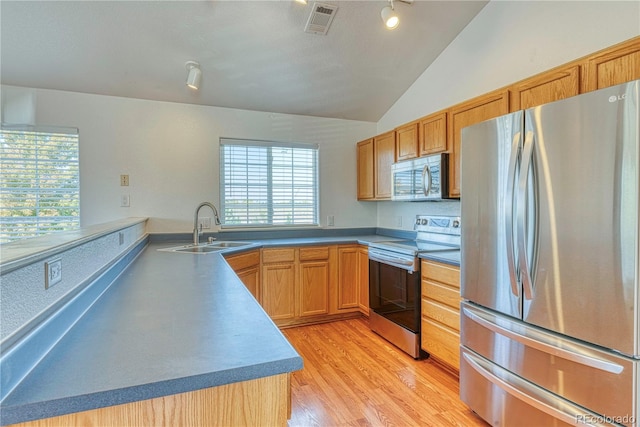 kitchen with stainless steel appliances, a sink, visible vents, light wood-style floors, and vaulted ceiling