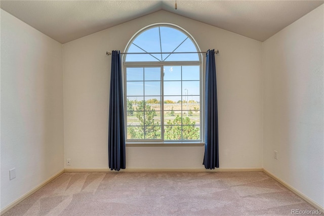 empty room with lofted ceiling, light colored carpet, and baseboards