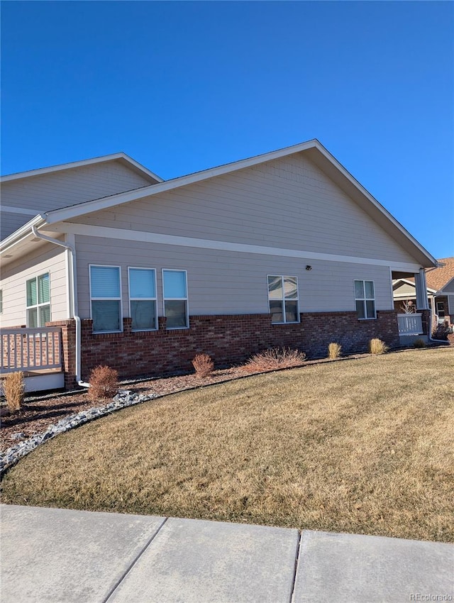 view of side of property featuring a lawn and brick siding