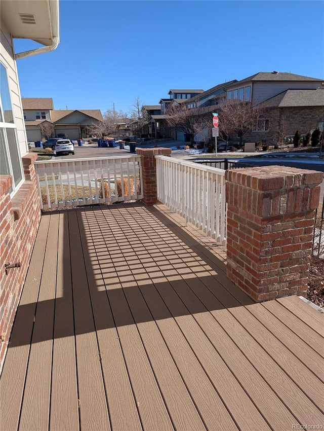 wooden deck featuring visible vents, covered porch, and a residential view
