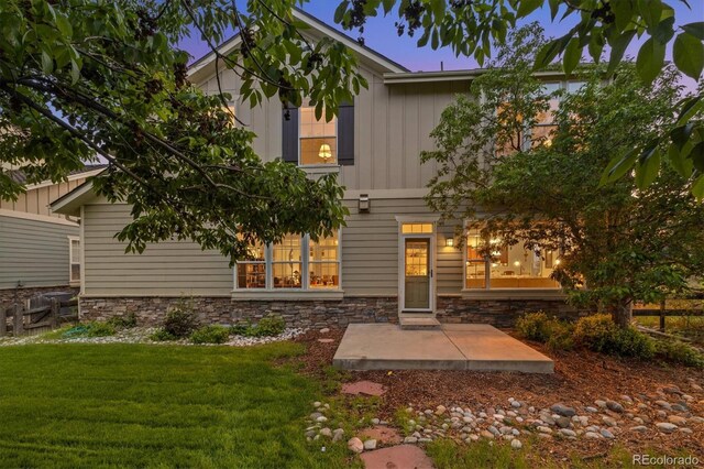 24422 E Frost Dr, Aurora, CO 80016 - back of house featuring stone siding, a yard, and board and batten siding