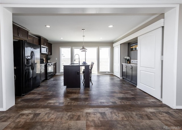 kitchen with a kitchen island with sink, sink, appliances with stainless steel finishes, dark brown cabinets, and dark hardwood / wood-style flooring