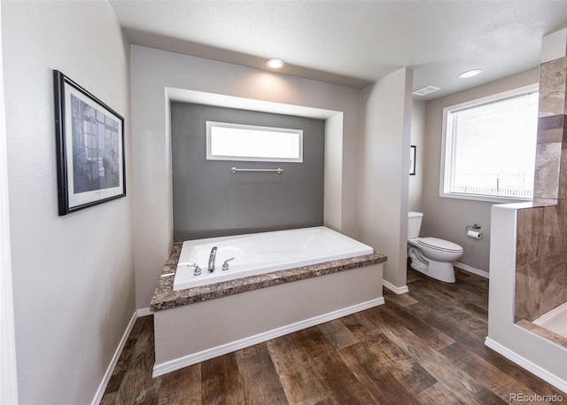 bathroom featuring a washtub, wood-type flooring, toilet, and a healthy amount of sunlight