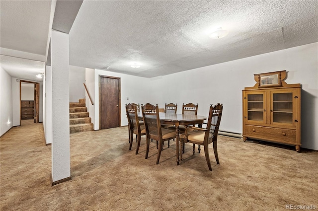 carpeted dining space with a baseboard radiator and a textured ceiling