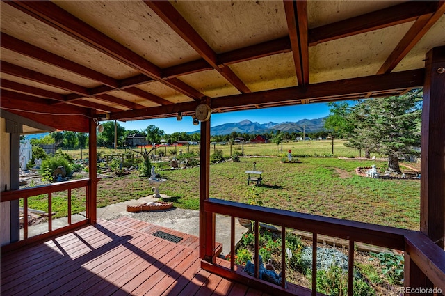 wooden deck with a mountain view and a yard