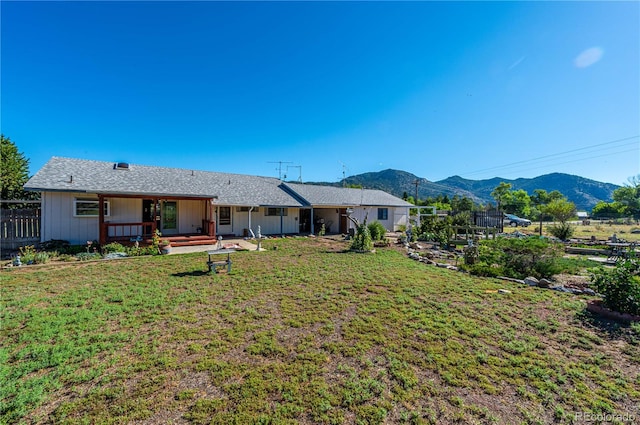 back of house with a mountain view and a lawn