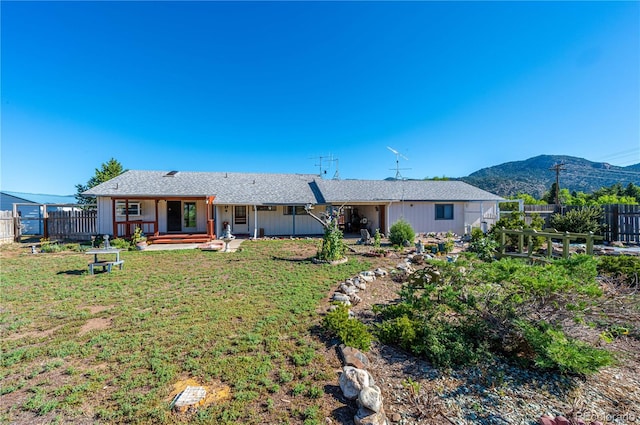 back of property featuring a mountain view and a lawn