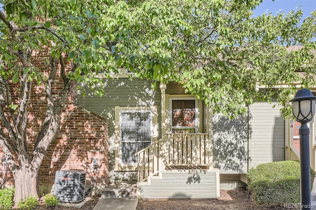 view of exterior entry with central air condition unit and brick siding