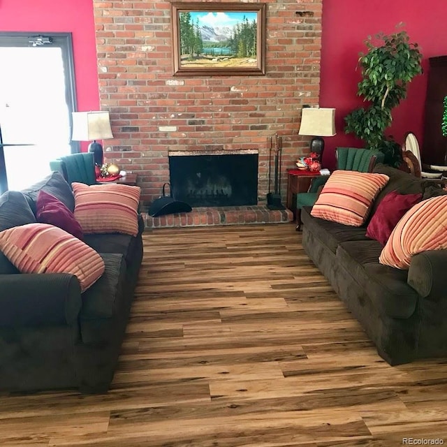 living room featuring a brick fireplace and wood finished floors