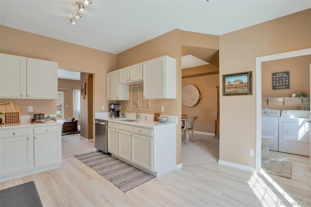 kitchen with washer and dryer, stainless steel dishwasher, a sink, and light wood-style flooring