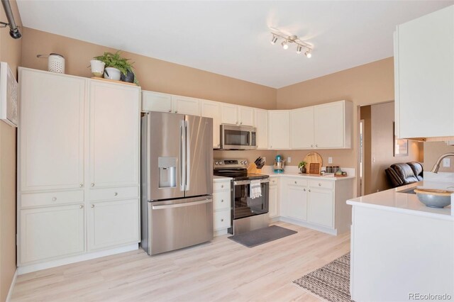 kitchen with light wood-type flooring, light countertops, white cabinetry, and appliances with stainless steel finishes