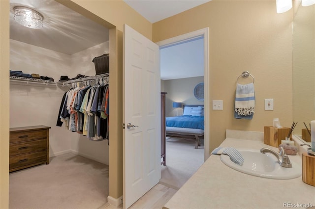 ensuite bathroom featuring vanity, connected bathroom, and a spacious closet