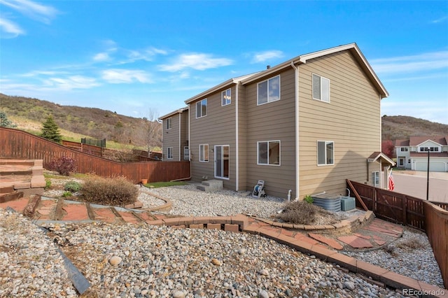rear view of property with cooling unit, a mountain view, and a fenced backyard