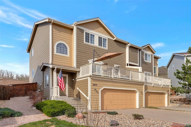 view of front of house with concrete driveway, fence, a balcony, and a garage