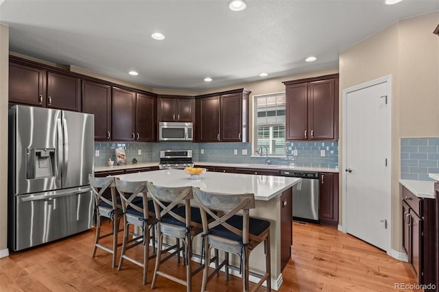 8272 E 55th Pl, Denver, CO 80238 - kitchen with stainless steel appliances, dark brown cabinetry, a breakfast bar, light wood-type flooring, and recessed lighting