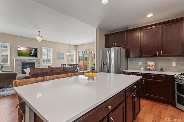 8272 E 55th Pl, Denver, CO 80238 - kitchen with stainless steel appliances, light countertops, light wood-style floors, open floor plan, and dark brown cabinetry