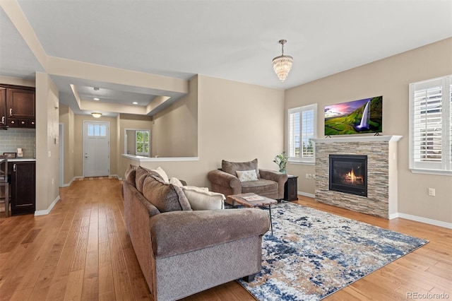 8272 E 55th Pl, Denver, CO 80238 - living room with a raised ceiling, light wood-style floors, and a stone fireplace