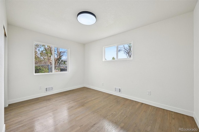 spare room featuring baseboards, visible vents, and wood finished floors