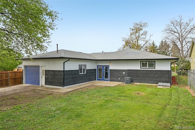 back of house featuring roof with shingles, fence, a yard, concrete driveway, and a garage