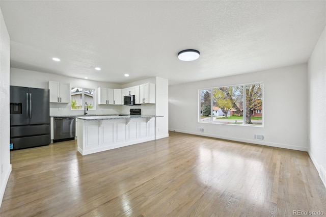 7780 Osceola St, Westminster, CO 80030 - kitchen with black appliances, healthy amount of natural light, light stone countertops, light wood-type flooring, and recessed lighting