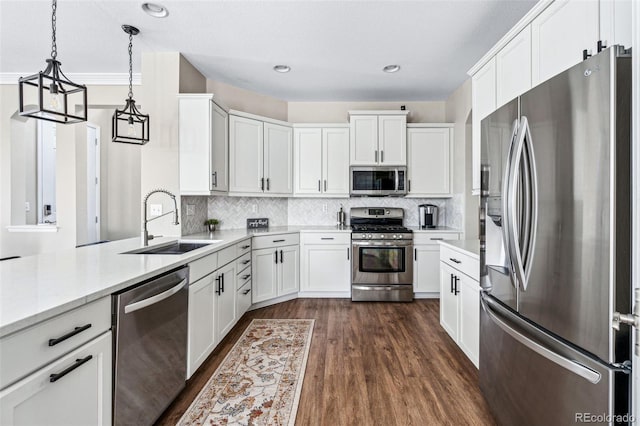 kitchen with pendant lighting, appliances with stainless steel finishes, sink, and white cabinets