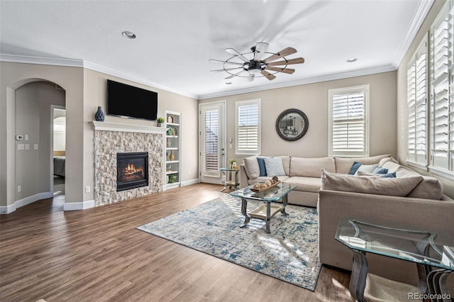 living room featuring crown molding, hardwood / wood-style floors, ceiling fan, and a fireplace