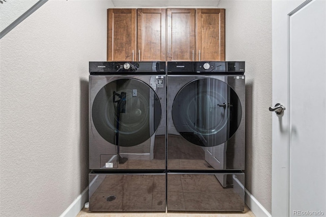 clothes washing area with washer and clothes dryer and cabinets