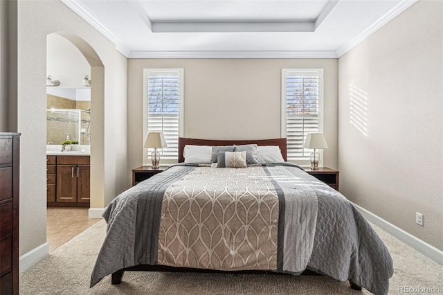 bedroom featuring crown molding, light carpet, ensuite bathroom, and a tray ceiling