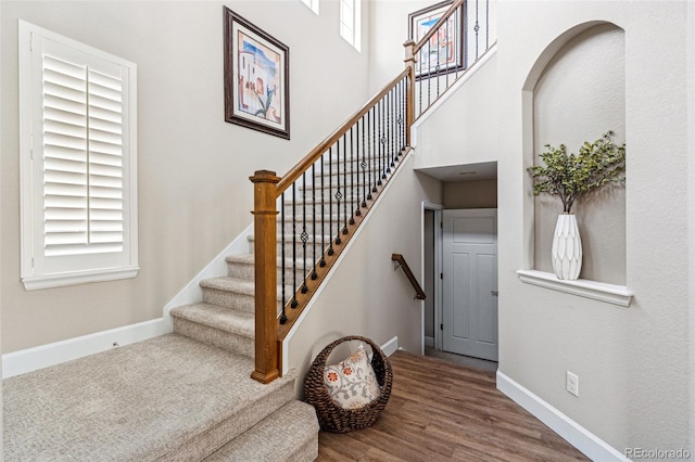 stairs featuring hardwood / wood-style flooring and a towering ceiling