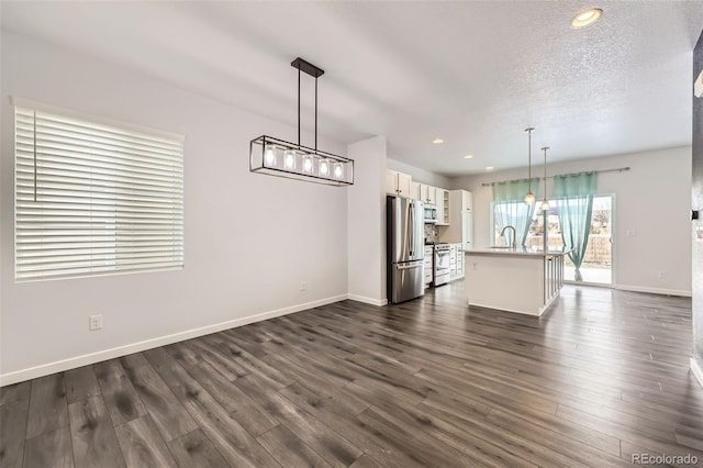 unfurnished living room featuring sink, an inviting chandelier, a textured ceiling, and dark hardwood / wood-style flooring