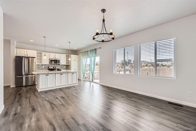 kitchen with pendant lighting, tasteful backsplash, light countertops, appliances with stainless steel finishes, and white cabinetry