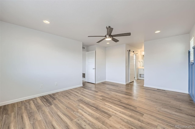 unfurnished room featuring baseboards, light wood-style flooring, recessed lighting, ceiling fan, and a barn door