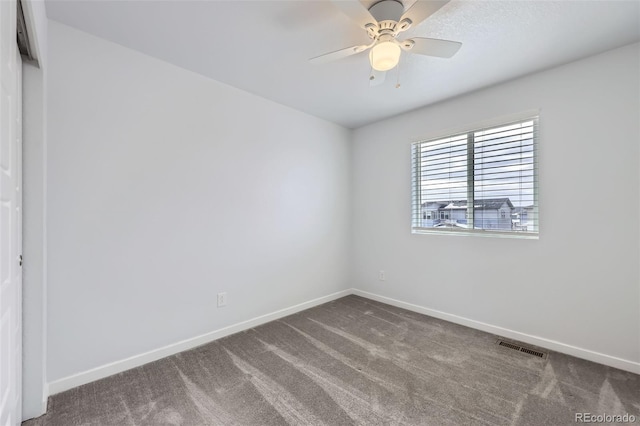 carpeted spare room with visible vents, baseboards, and a ceiling fan