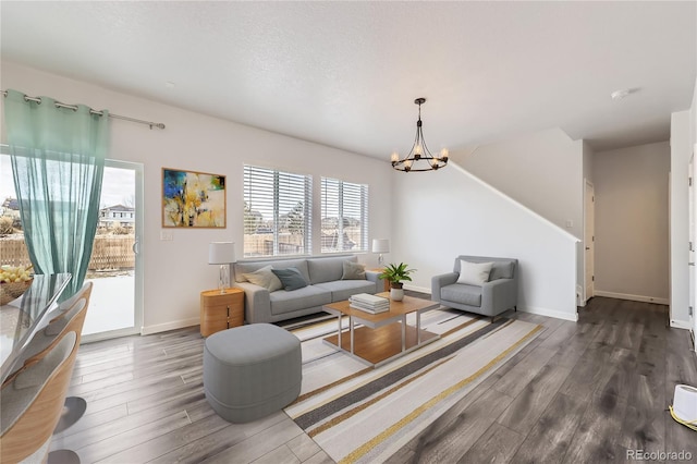 living room featuring a chandelier, dark wood-style flooring, a textured ceiling, and baseboards