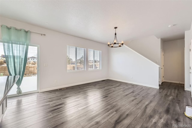 interior space with dark wood-style floors, a notable chandelier, and baseboards