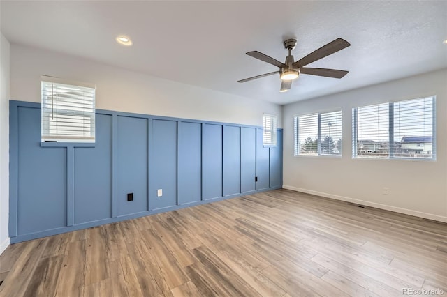 empty room featuring ceiling fan, recessed lighting, a decorative wall, visible vents, and light wood-style floors