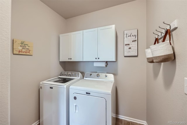 washroom with washing machine and dryer, baseboards, and cabinet space