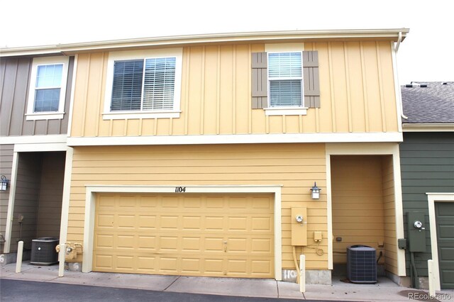 view of front of property featuring board and batten siding, an attached garage, and central air condition unit