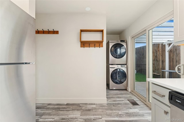 6495 E Happy Canyon Rd Unit 158, Denver, CO 80237 - laundry room with stacked washer and clothes dryer, light wood finished floors, and baseboards