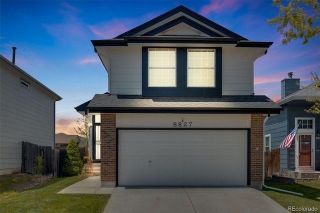 traditional home featuring concrete driveway, brick siding, an attached garage, and fence