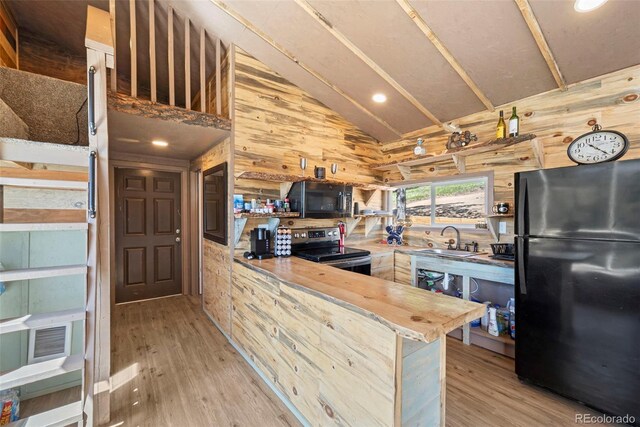 161 Highland Cir, Rye, CO 81069 - kitchen featuring black appliances, a sink, wood walls, a peninsula, and light wood-style floors