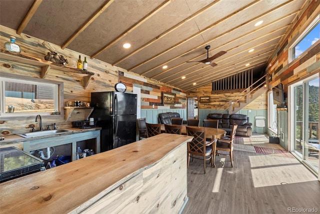 161 Highland Cir, Rye, CO 81069 - kitchen with freestanding refrigerator, a sink, wooden walls, lofted ceiling, and wood finished floors