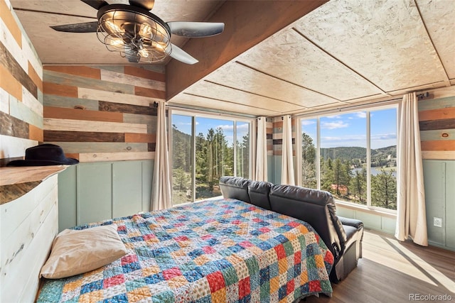 161 Highland Cir, Rye, CO 81069 - bedroom featuring multiple windows, wood walls, wood finished floors, a mountain view, and ceiling fan